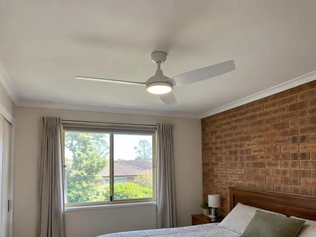 Ceiling fan on a bedroom ceiling above a brick feature wall and window with curtains in Cardiff South
